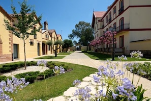 A courtyard with buildings, a pathway, and flowering plants.