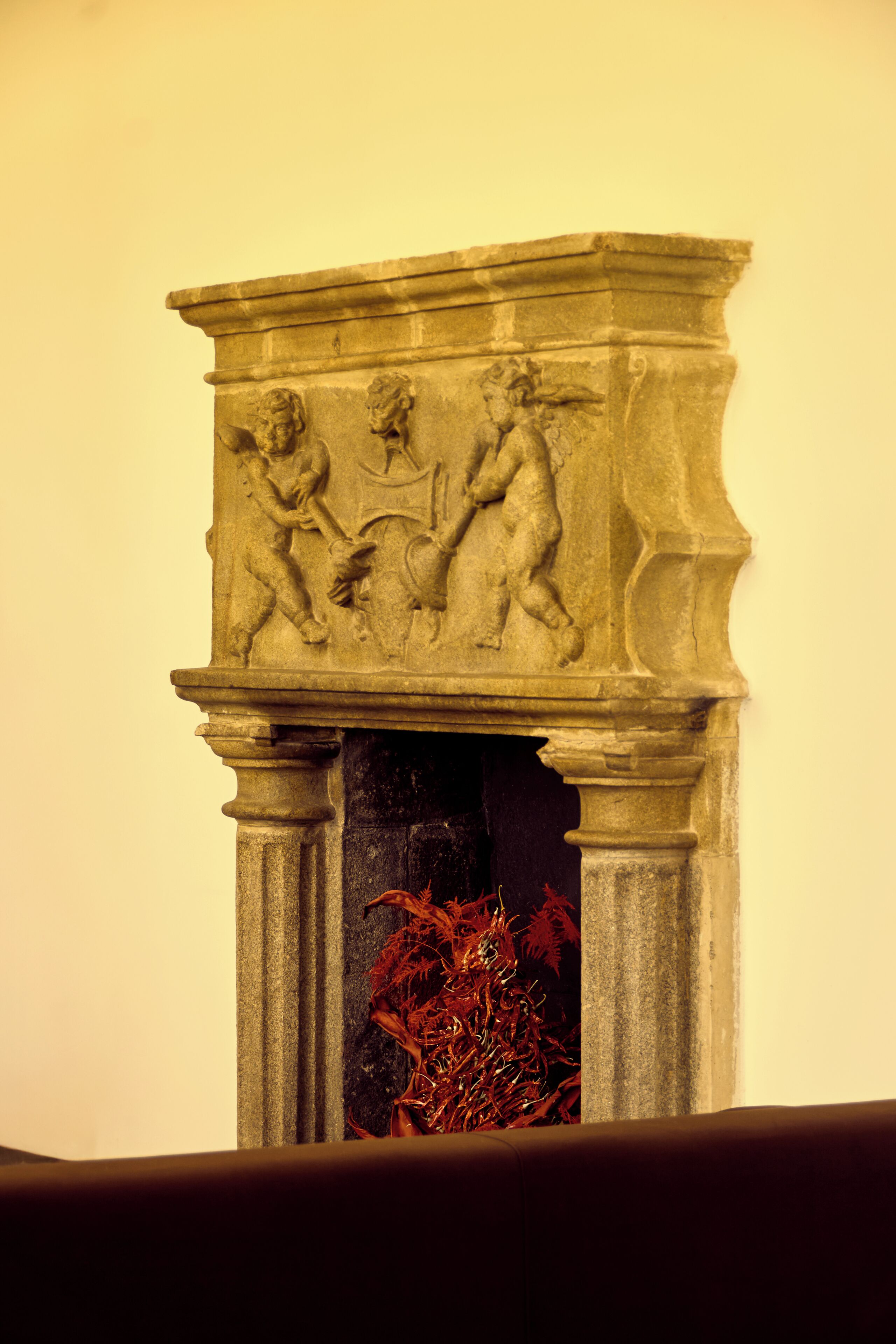 Een stenen constructie met gebeeldhouwde figuren, mogelijk een open haard of architectonisch detail.
