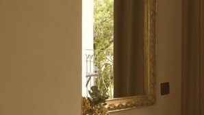 Un espejo con un marco decorado, un florero con flores y una encimera de mármol.