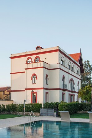 A large building with a swimming pool in front.