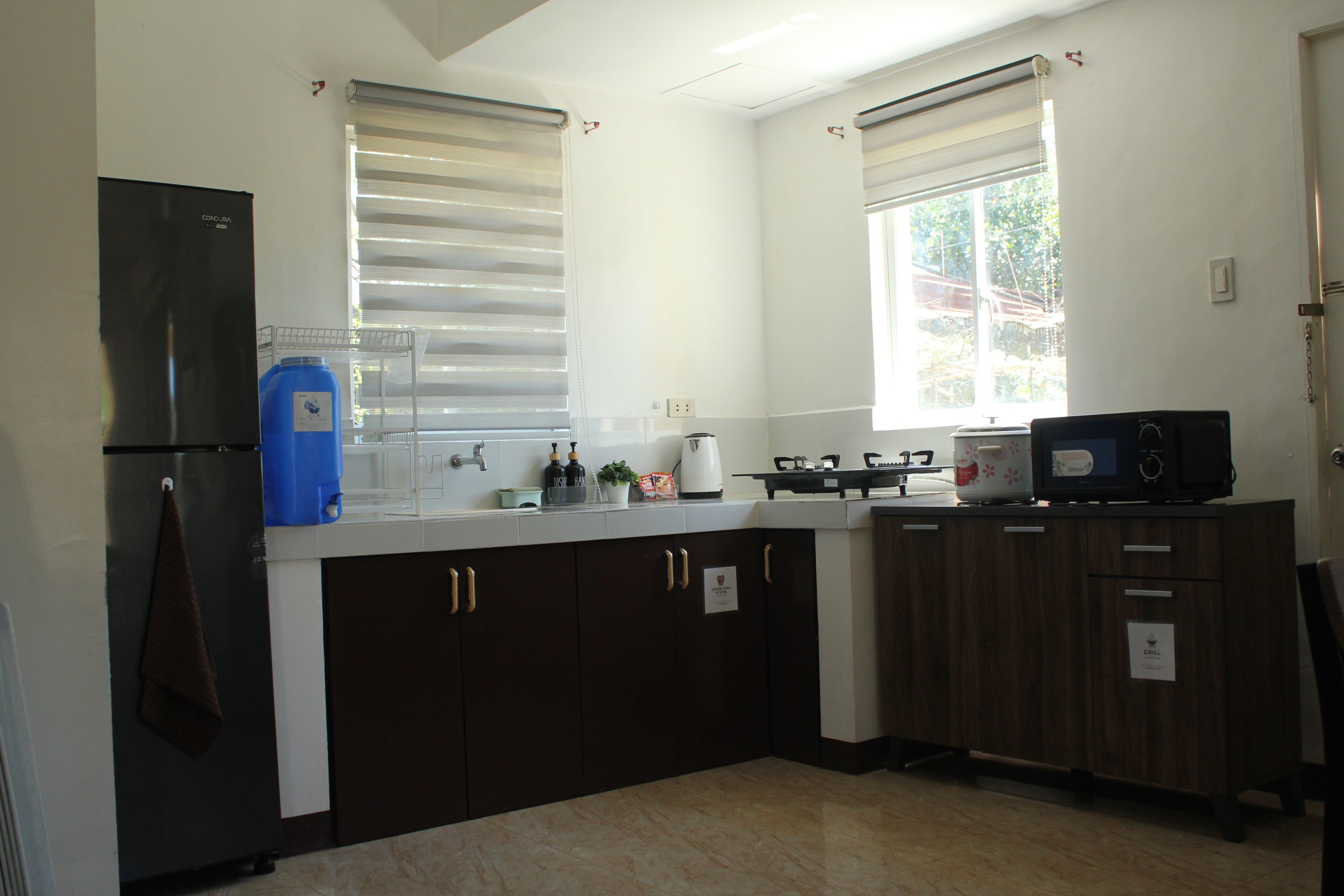 A kitchen with a refrigerator, sink, stove, microwave, and cabinets.