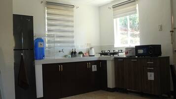 A kitchen with a refrigerator, sink, stove, microwave, and cabinets.