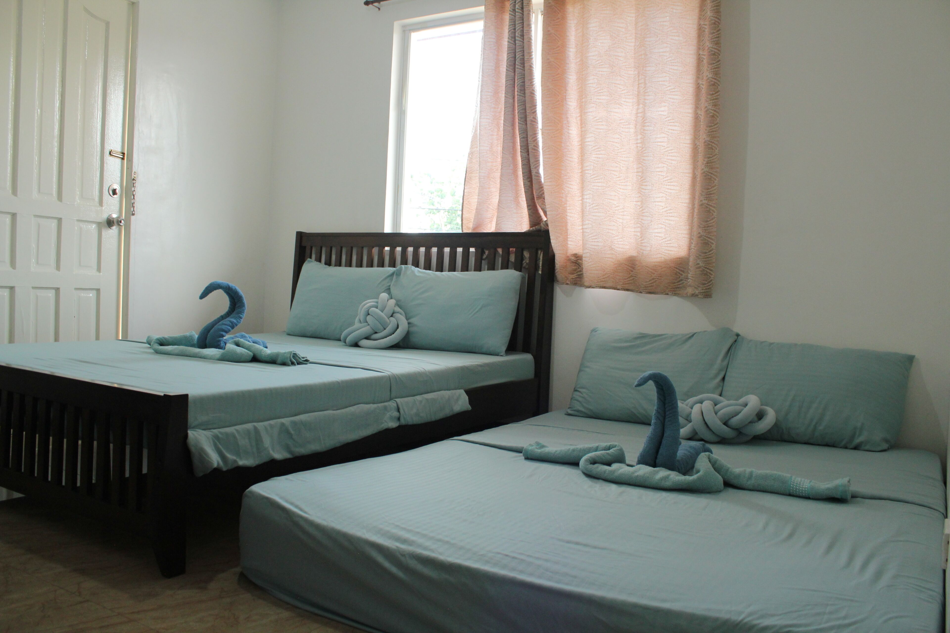 A room with two beds, each with a headboard and pillows.