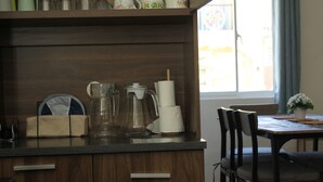 En köksbänk med en kaffebryggare, en glaskanna och en korg.