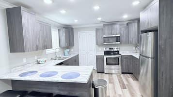 A modern kitchen with a central island, stainless steel appliances, and wooden flooring.