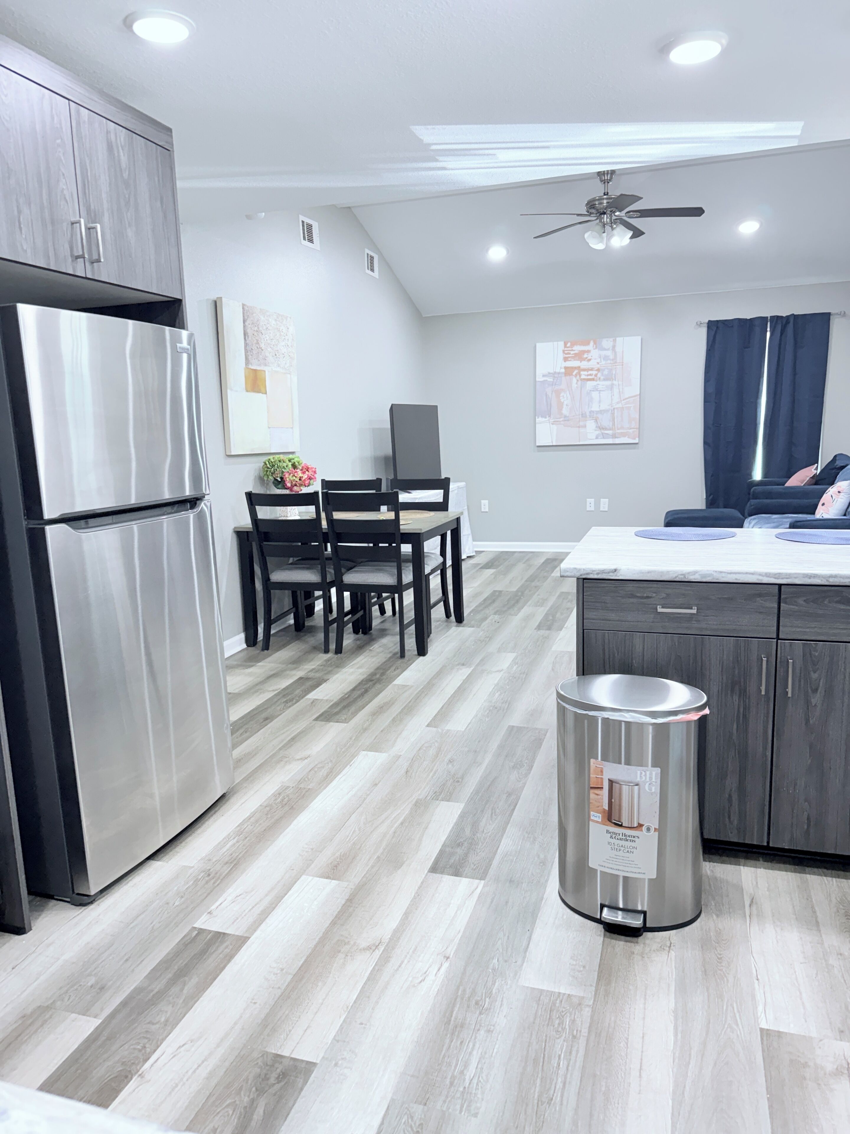 Una cocina moderna con refrigerador empotrado, un comedor con mesa y sillas, y un ventilador de techo.