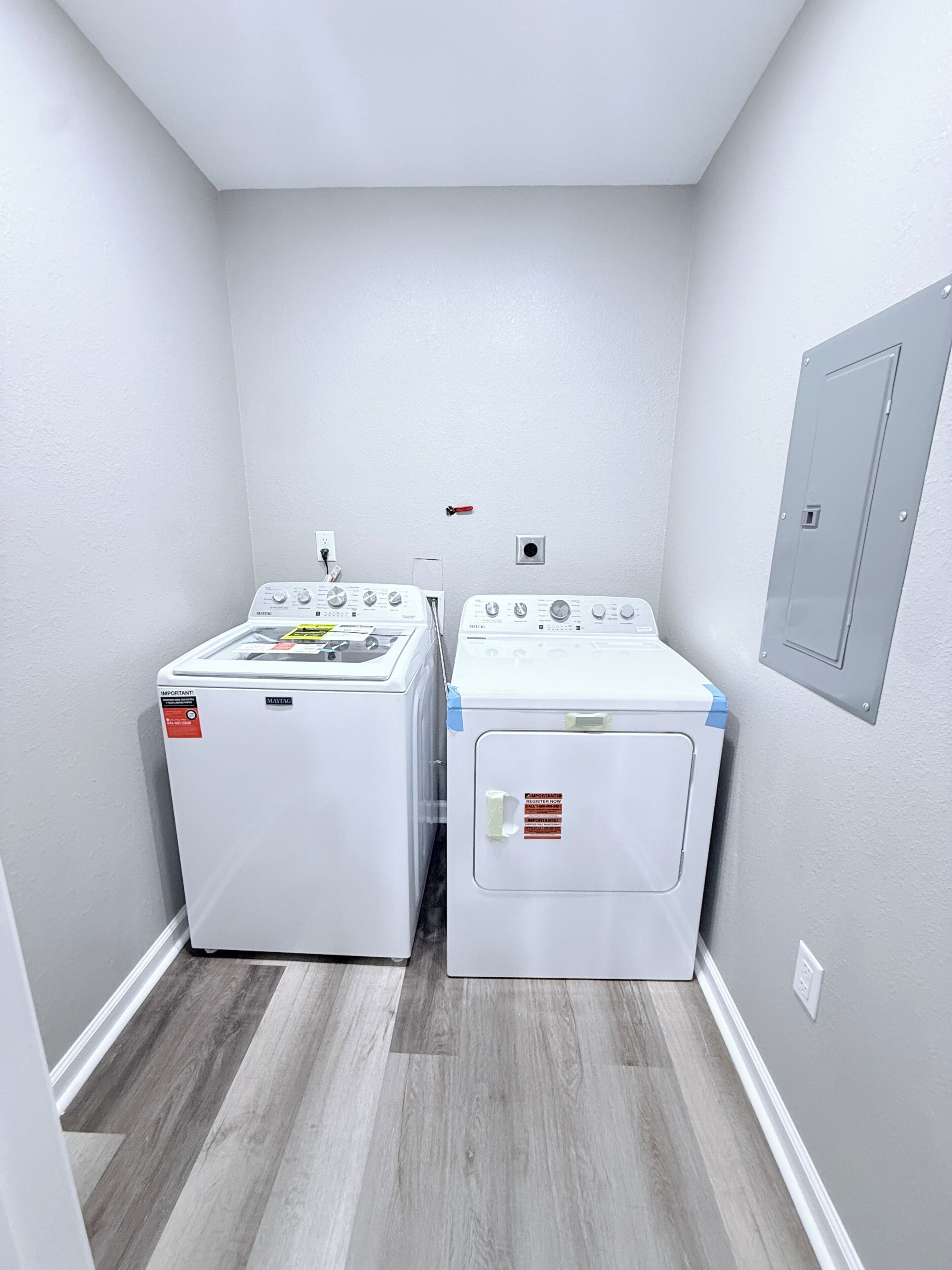 A laundry room with two front-loading washing machines and a utility wall with a door.