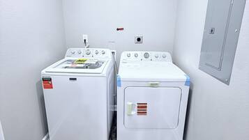 A laundry room with two front-loading washing machines and a utility wall with a door.