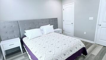 A bedroom with a bed, nightstands, a ceiling fan, and a door.