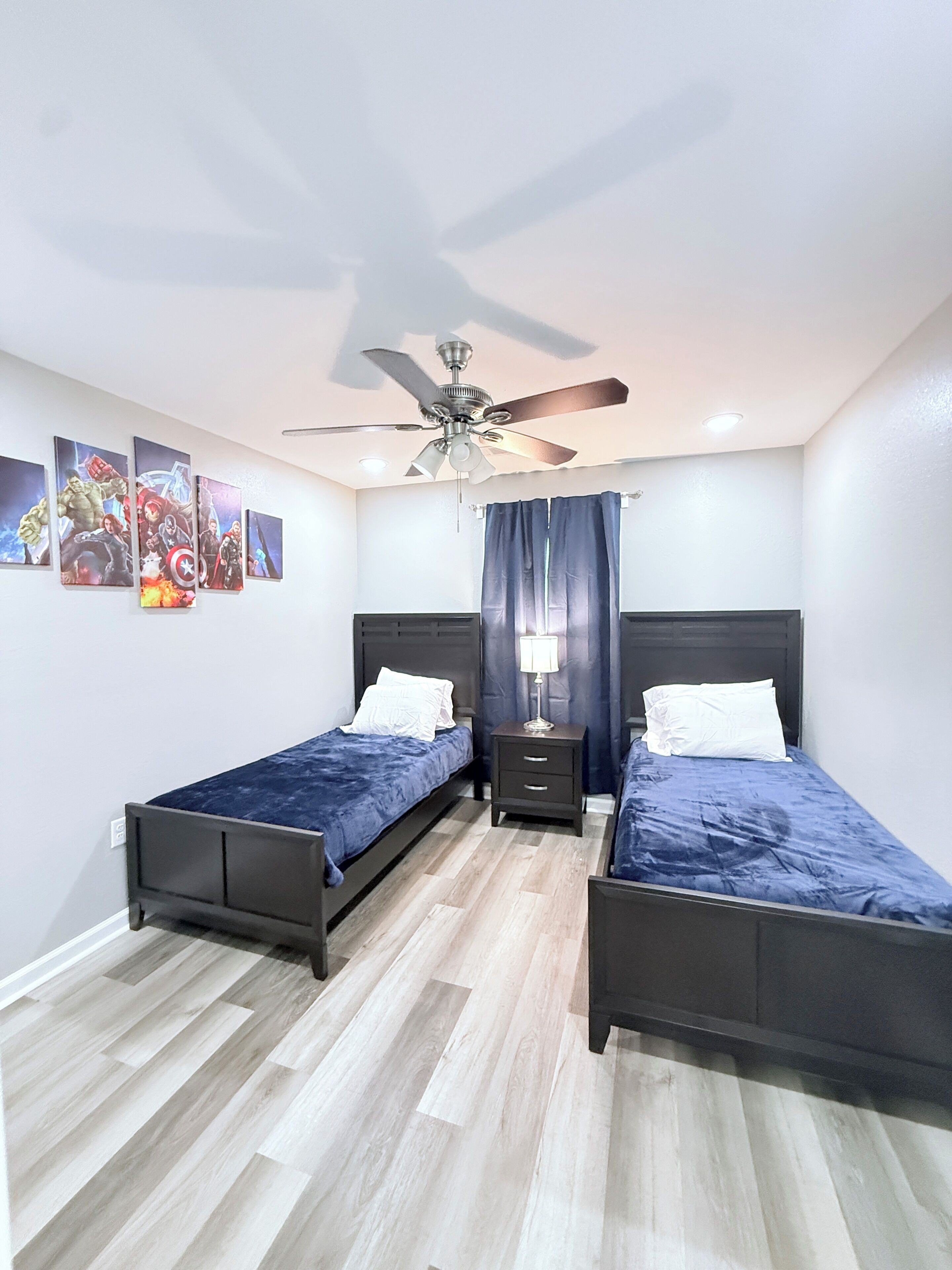 Een slaapkamer met twee bedden, een plafondventilator en wanddecoratie.