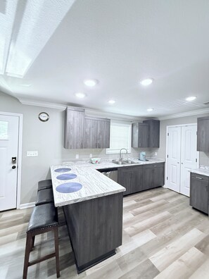 A modern kitchen with a central island, built-in cabinets, and a window with blinds. - Heart of Heber Springs near everything (Heber Springs)