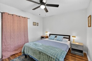 A bedroom with a bed, two bedside tables, a ceiling fan, and a window with a curtain. - Cute Clean 1br Close to the Quarter #3 (New Orleans)
