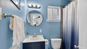 Un bagno con lavandino, specchio, WC e tenda della doccia.
