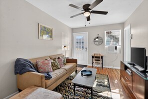 A living room with a sofa, a coffee table, a television, and a ceiling fan. - Cute Clean 1br Close to the Quarter #3 (New Orleans)