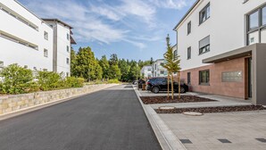 Une rue résidentielle bordée de bâtiments modernes, avec une chaussée pavée et un ciel dégagé.