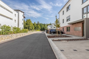 Une rue résidentielle bordée de bâtiments modernes, avec une chaussée pavée et un ciel dégagé.