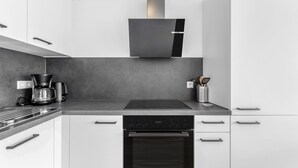 Une cuisine moderne équipée d’un four encastré, d’une machine à café et d’une hotte aspirante.