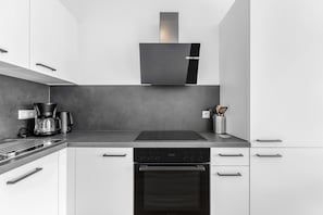 Une cuisine moderne équipée d’un four encastré, d’une machine à café et d’une hotte aspirante.