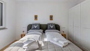 Une chambre avec deux lits, une grande armoire et une fenêtre.