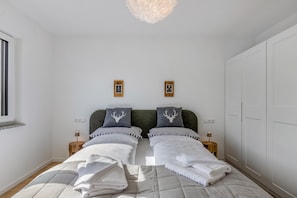 Une chambre avec deux lits, une grande armoire et une fenêtre.