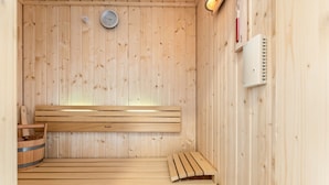 Un sauna en bois avec un banc, un thermomètre fixé au mur et un petit radiateur.