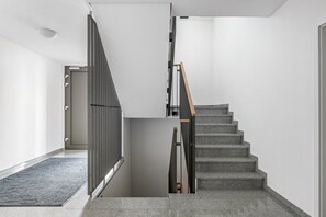 Una escalera moderna con descansillo alfombrado en gris y barandilla de madera.