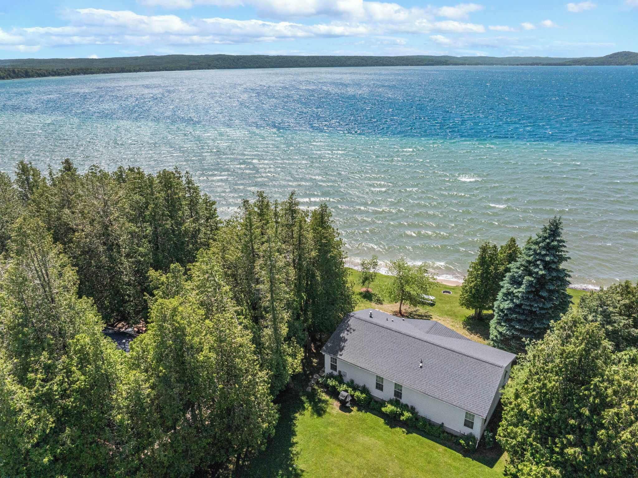 A house with a view of a large body of water, surrounded by dense forest.