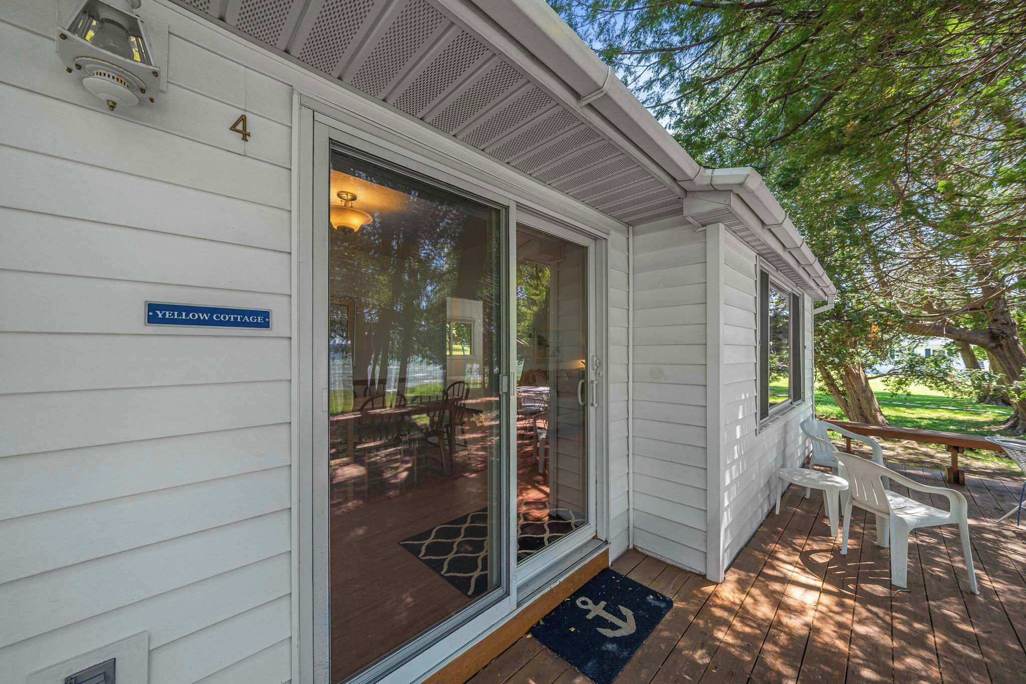 A single-story building with a sliding glass door entrance, a porch with outdoor seating, and a blue sign indicating 'YELLOW COTTAGE.'