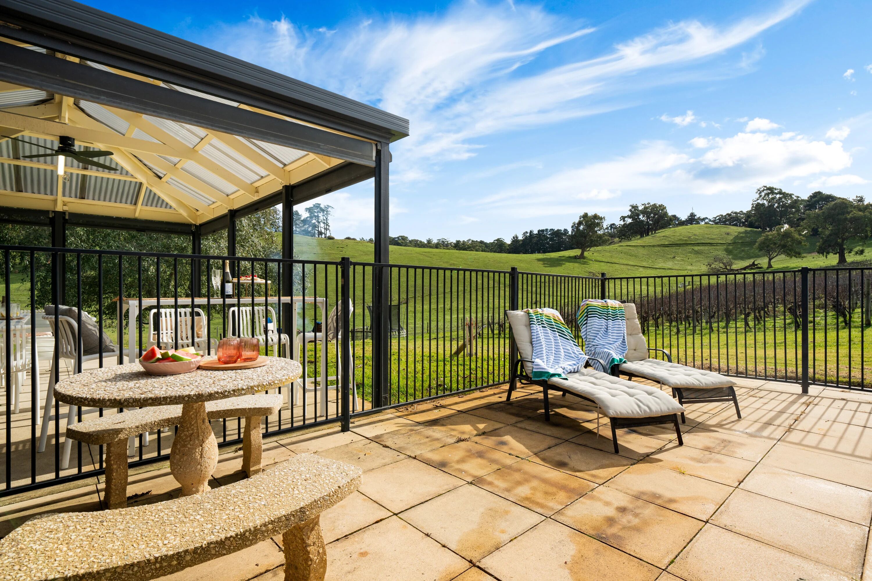 Une terrasse couverte avec une table et des chaises, une pergola et une vue sur un paysage verdoyant.