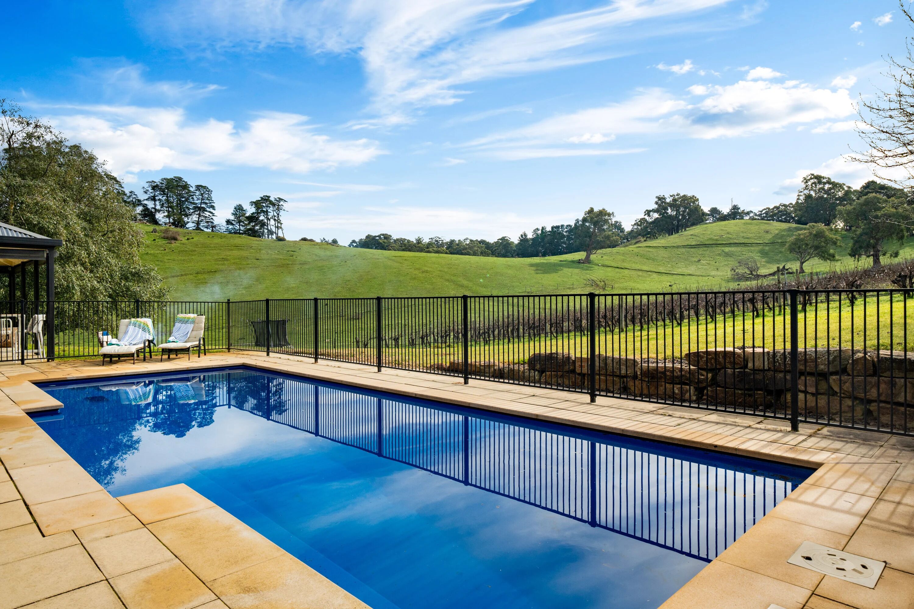 A swimming pool with a view of a green landscape and a stone wall.