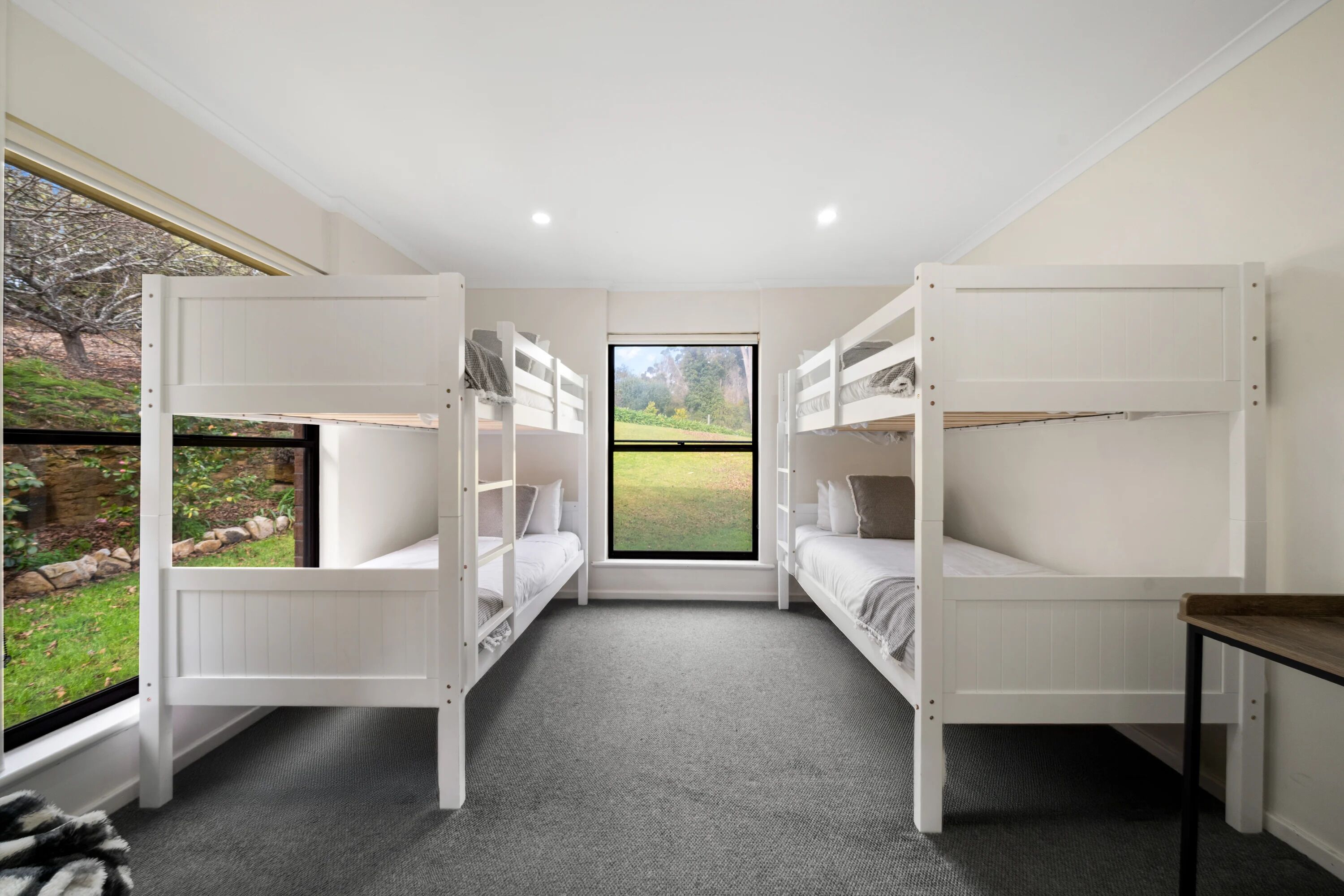 Une chambre avec deux lits superposés, une fenêtre donnant sur un jardin et une petite table.