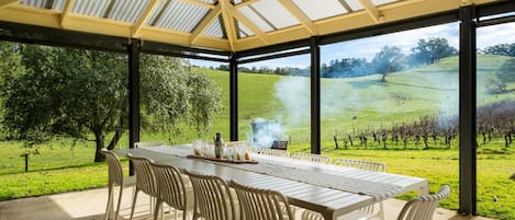 An outdoor patio with a table and chairs, a ceiling fan, and a view of a vineyard.