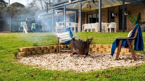 Ein Terrassenbereich im Freien mit Grill, Sitzgelegenheiten und einer überdachten Essgruppe.