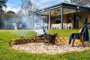 Ein Terrassenbereich im Freien mit Grill, Sitzgelegenheiten und einer überdachten Essgruppe.