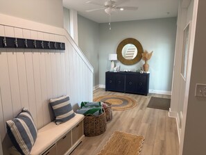 A modern interior with a bench, a round mirror, a dark-colored cabinet, and a ceiling fan. - Sweet SeaRenity- SURF CITY -New Luxury 4B, Ocean Views, Steps to Beach, Elevator (Surf City)
