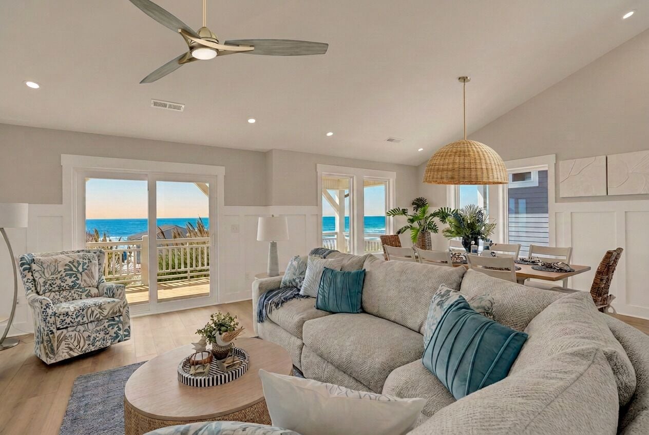 A spacious living room with a large sofa, a coffee table, and a ceiling fan.