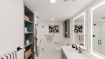 A modern bathroom with a white sink, a large mirror, and a shower area.