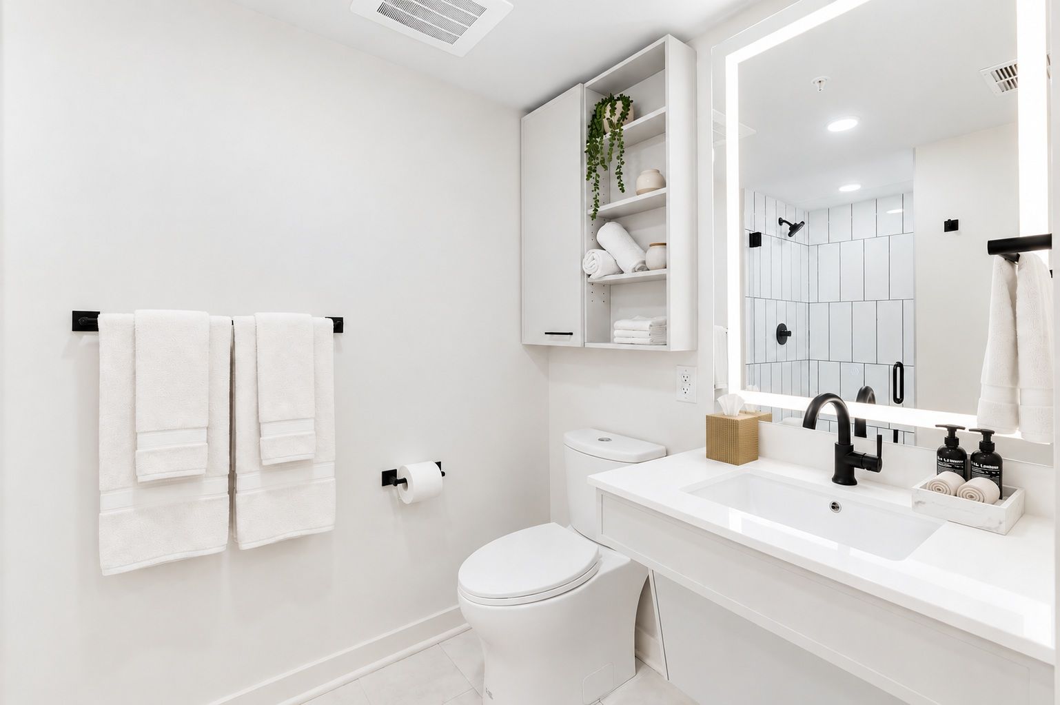 A modern bathroom with white fixtures, a toilet, a sink with a mirror, and two towels hanging on a rack.