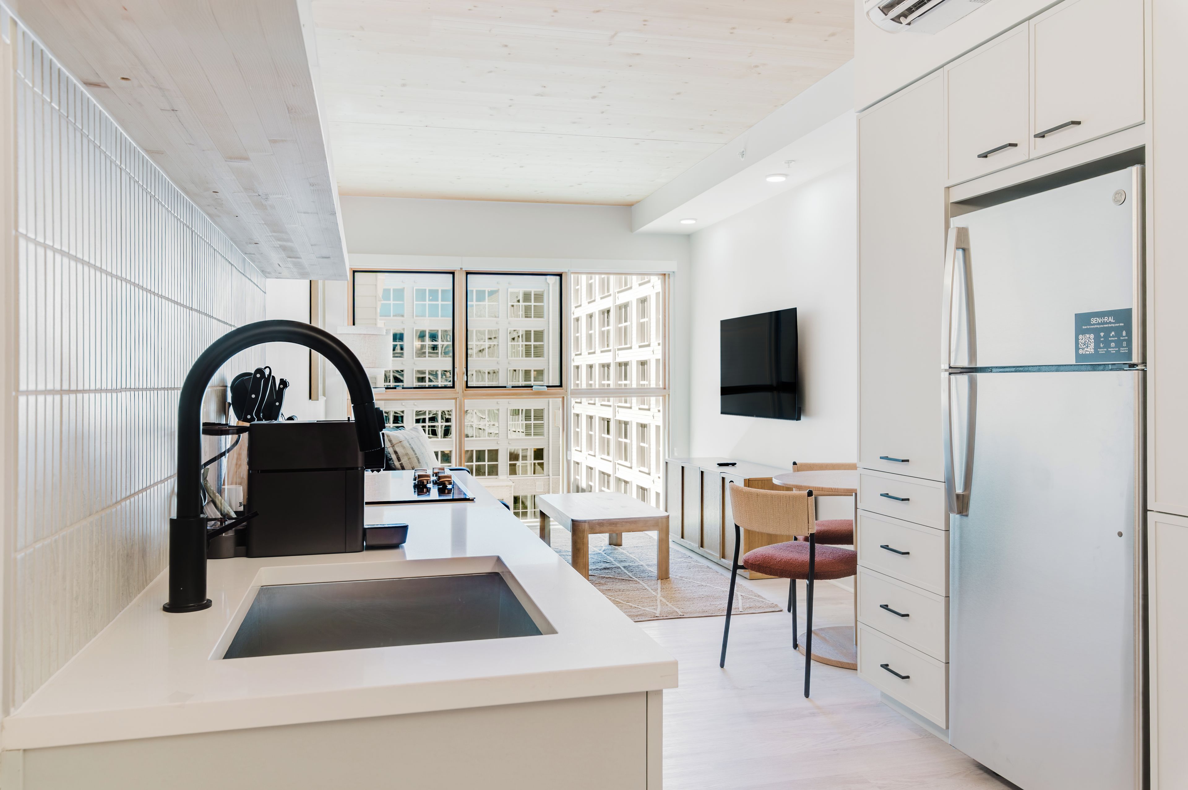 A modern kitchen with a built-in island, a refrigerator, and a dining area with a table and chairs.