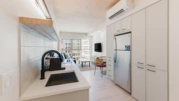A modern kitchen with white cabinetry, a built-in stove, and a large refrigerator.