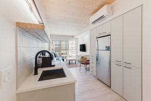 A modern kitchen with white cabinetry, a built-in stove, and a large refrigerator.