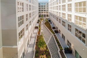 A multi-story building with a central courtyard featuring a landscaped garden and a patterned walkway.