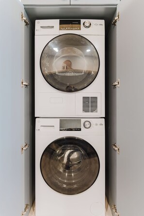 A stacked washer and dryer unit with a control panel and a reflective glass door.