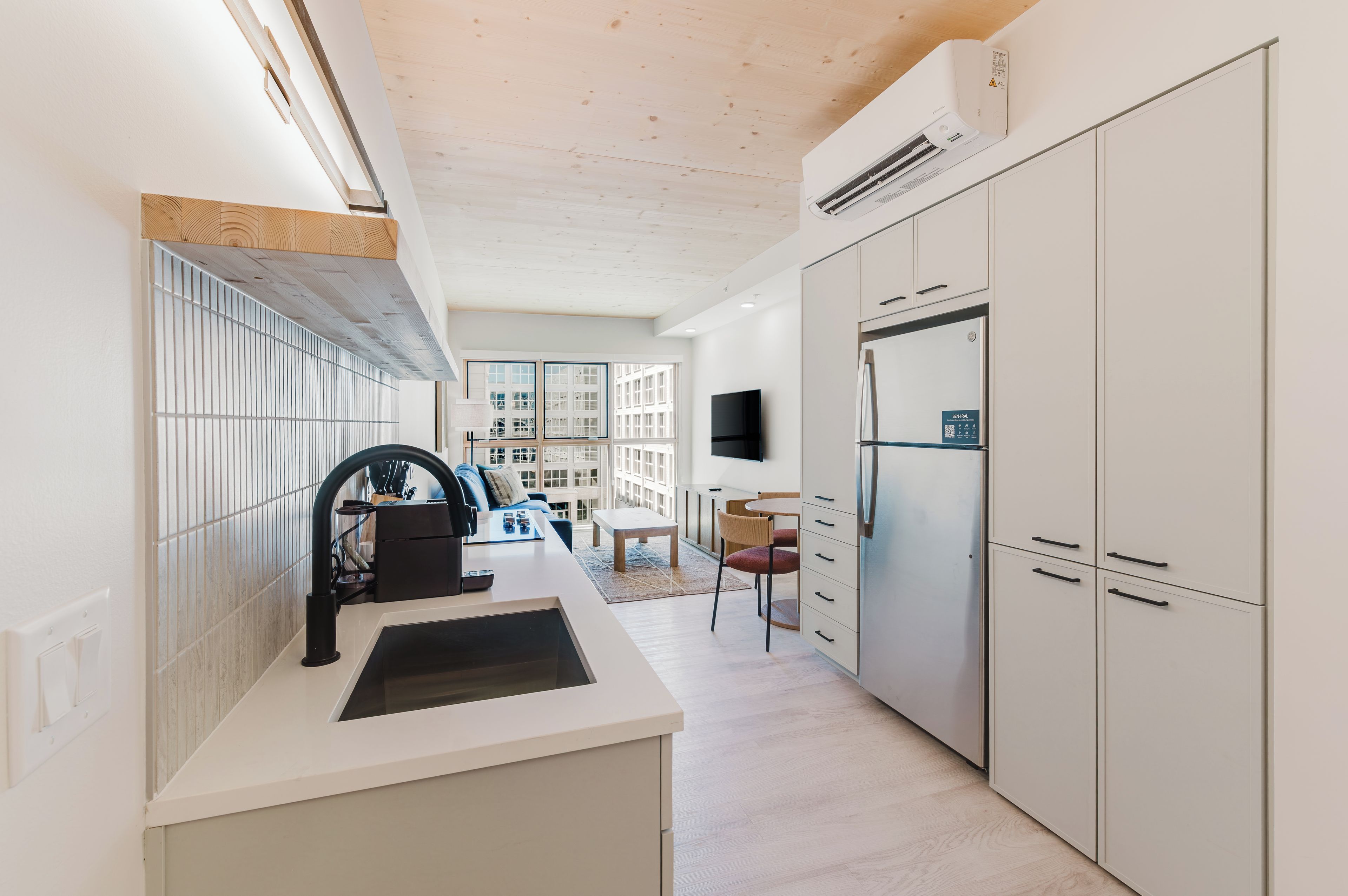 A modern kitchen with a built-in stove, a refrigerator, and a dining area with a table and chairs.