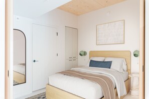 A bedroom with a bed, a door, a wall-mounted light fixture, and a framed picture.