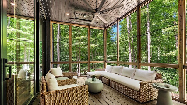 A covered outdoor seating area with wicker furniture and a view of the forest. - The Linehouse at Norstead (Cedar)