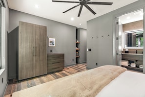 Quarto com cama, guarda-roupa, cômoda, ventilador de teto e uma janela grande.