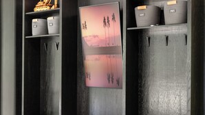 A room with a wooden cabinet, a framed picture, and storage baskets. - The Linehouse at Norstead (Cedar)