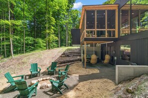 Uma casa moderna com varanda, área de estar externa e um cenário de floresta.