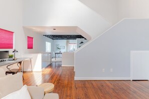 A modern living space with a wooden floor, a dining area, and a kitchen with a visible ceiling structure. - Urban Luxe Escape - Stylish & Serene (Houston)